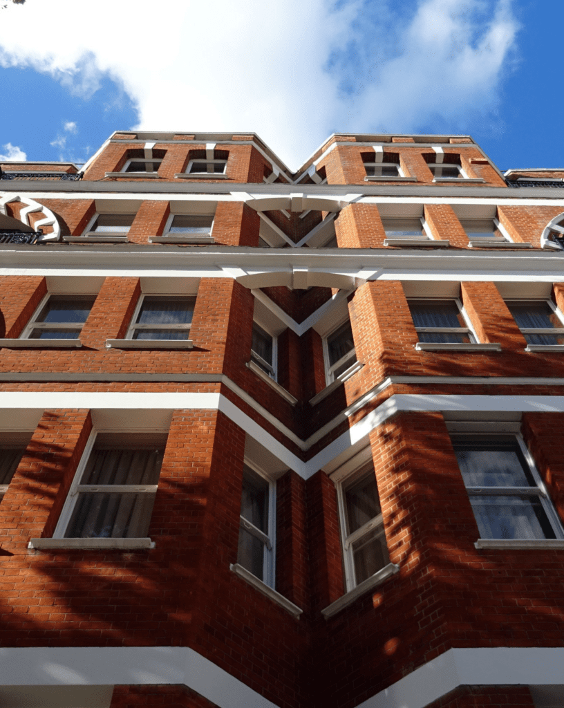 Stone Haven Developments A low-angle view of a red brick building with white trim, multiple windows, and a blue sky with scattered clouds in the background, showcasing the architectural expertise of Stone Haven Developments. Ontario
