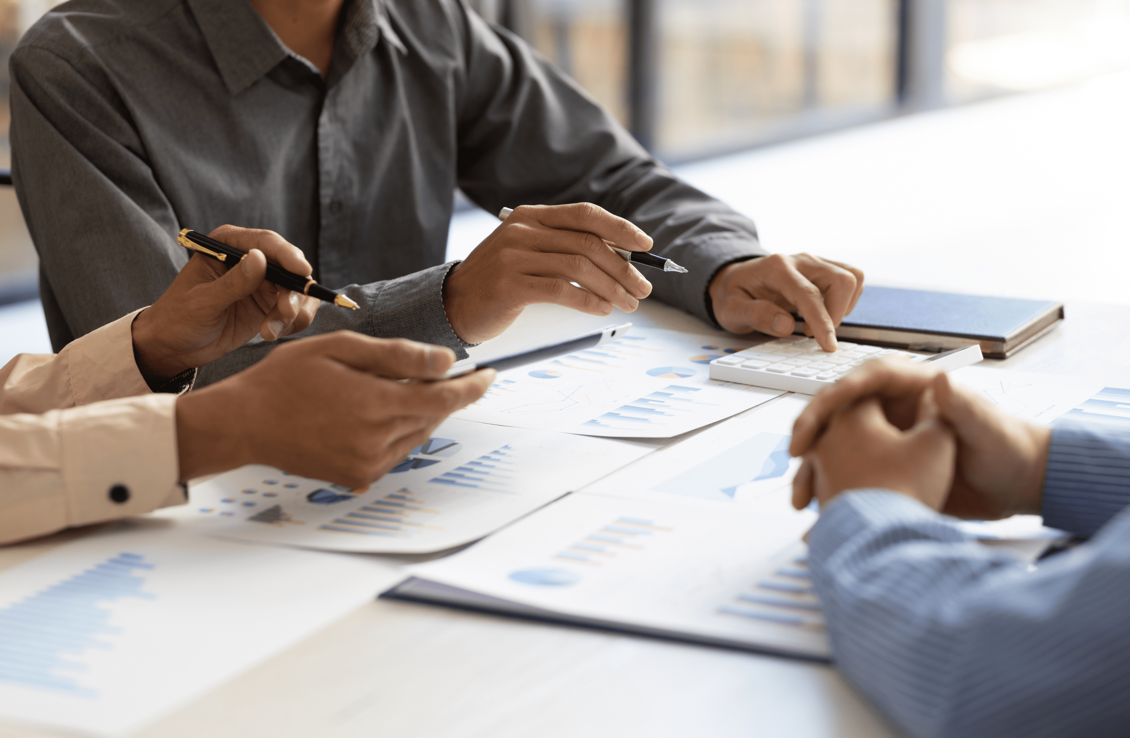 Stone Haven Developments Three people in business attire sit at a table, reviewing financial charts and graphs for Stone Haven Developments, with one using a calculator and others holding pens and documents. Ontario