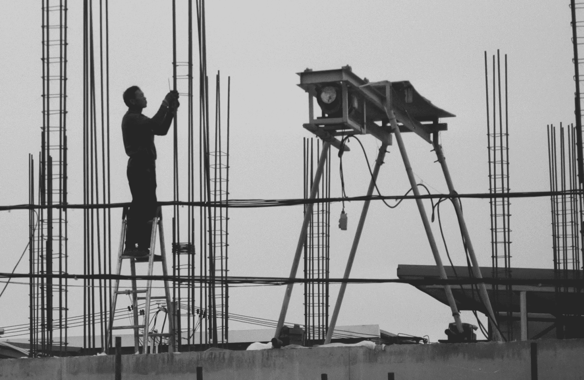 Stone Haven Developments A person stands on a ladder tying steel reinforcement rods at a construction site, with building materials and equipment visible in the background. Ontario