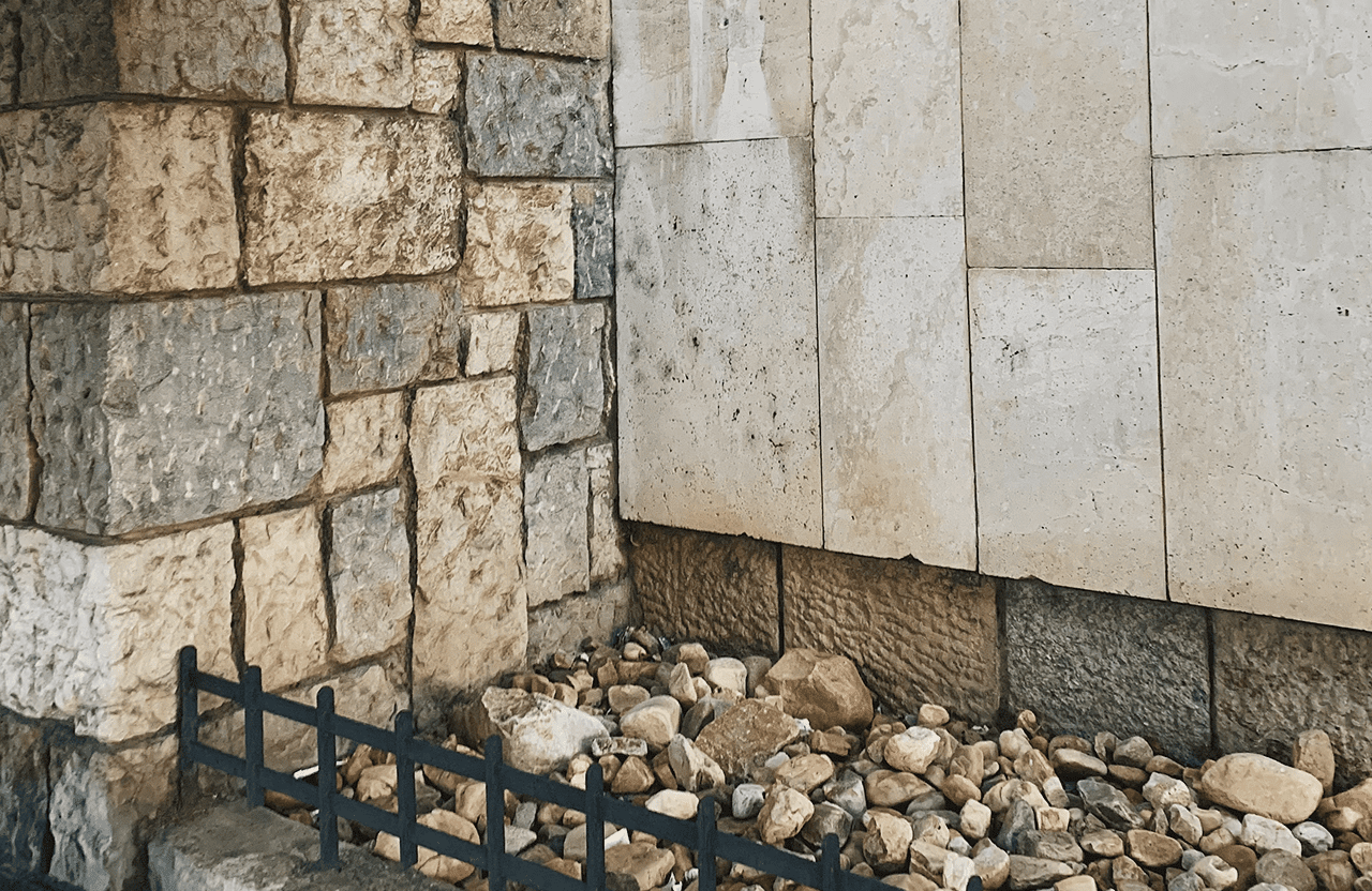 Stone Haven Developments A small iron fence borders a bed of assorted rocks in front of a stone wall and a concrete wall. Ontario